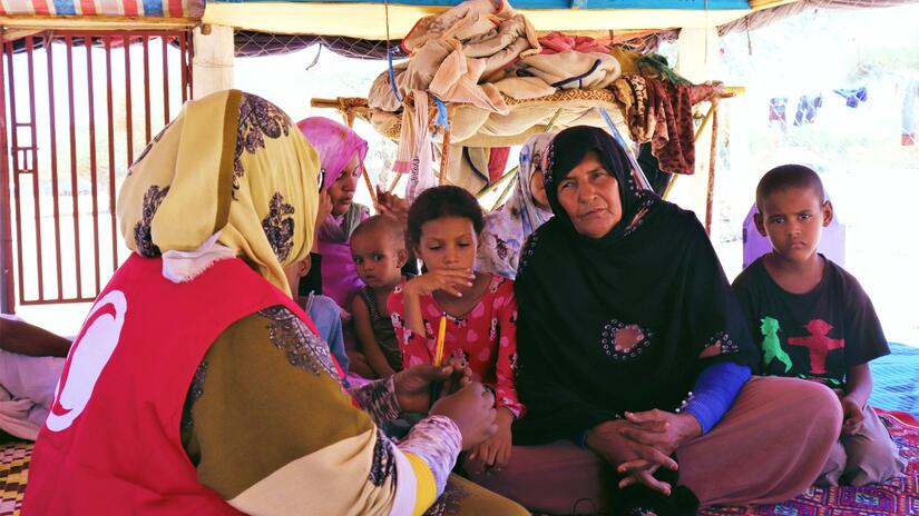 متطوعة في الهلال الأحمر الموريتاني تتحدث إلى أرملة، هي زينب، في تامورت النعاج، موريتانيا؛ تعتمد زينب حاليًا على أقاربها للبقاء على قيد الحياة وإطعام أطفالها خلال فترة انعدام الأمن الغذائي في البلاد. 