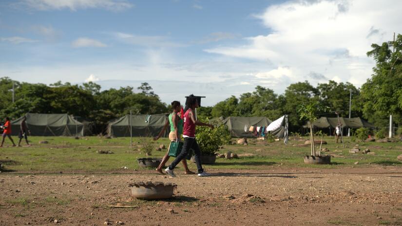 Two men carry a crate of supplies through the migrant camp they're sheltering in on the border between Costa Rica and Nicaragua.