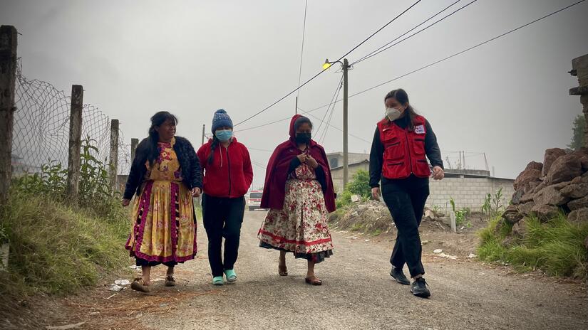ثلاث نساء من اللجنة الصحية المحلية في زيكاراكوخ، غواتيمالا، يمشون بصحبة أحد موظفي الاتحاد الدولي لجمعيات الصليب الأحمر والهلال الأحمر. 