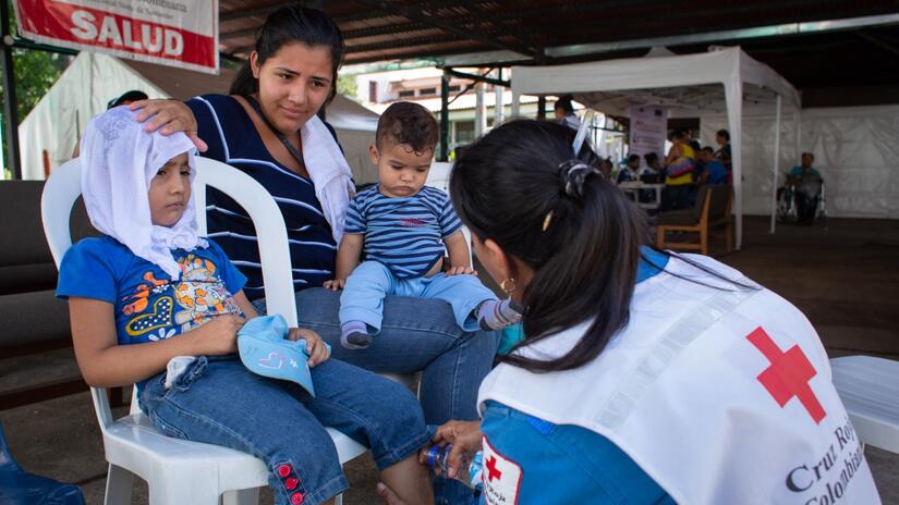 Bianca from San Cristobal, Venezuela gets help from a Colombian Red Cross medical volunteer in Cucuta who checks up on her two young children.