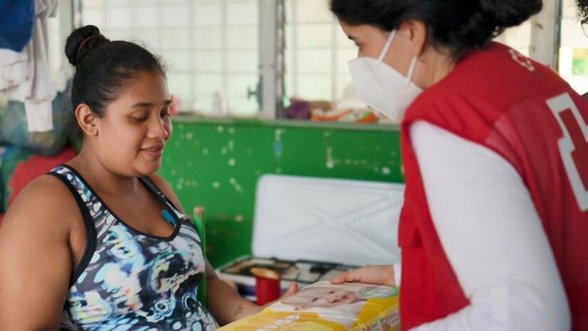 Eva Turró hands a pack of baby diapers to a mother in Honduras to help her family after Hurricanes Eta and Iota smashed into Central America in December 2020.