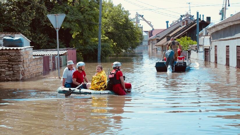 Personal voluntario de la Cruz Roja Ucraniana rescatan a un hombre y una mujer de las aguas de la inundación en una pequeña embarcación el 6 de junio, tras el colapso de la presa de Nova Kakhovka.