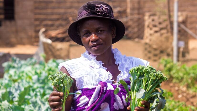 New mother, Beauty Manyazda, holds up lettuces she has picked from the garden at the Chibuwe Clinic, Zimbabwe.