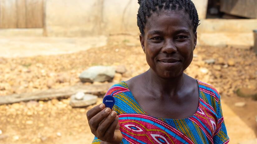 Joyce holds up the rechargeable token she uses to buy water from the water pump.