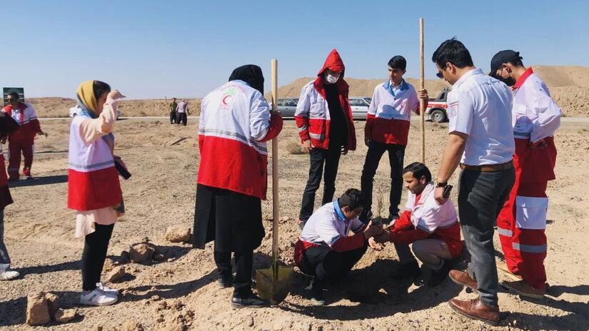 Personal voluntario de la Media Luna Roja Iraní trabaja para plantar árboles jóvenes en una zona rural de Irán en la primavera de 2023.