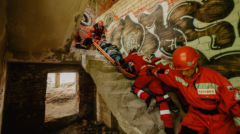 فريق من المنقذين يقوم بحمل المصاب بحذر على الدرج أثناء التدريب على الكوارث. 