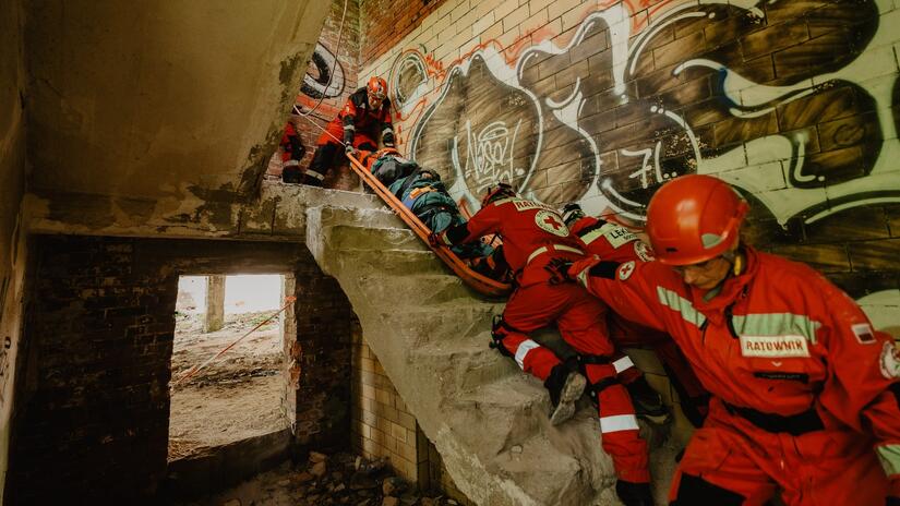 Une équipe de sauveteurs transporte avec précaution une personne blessée dans un escalier lors d'un exercice de catastrophe.