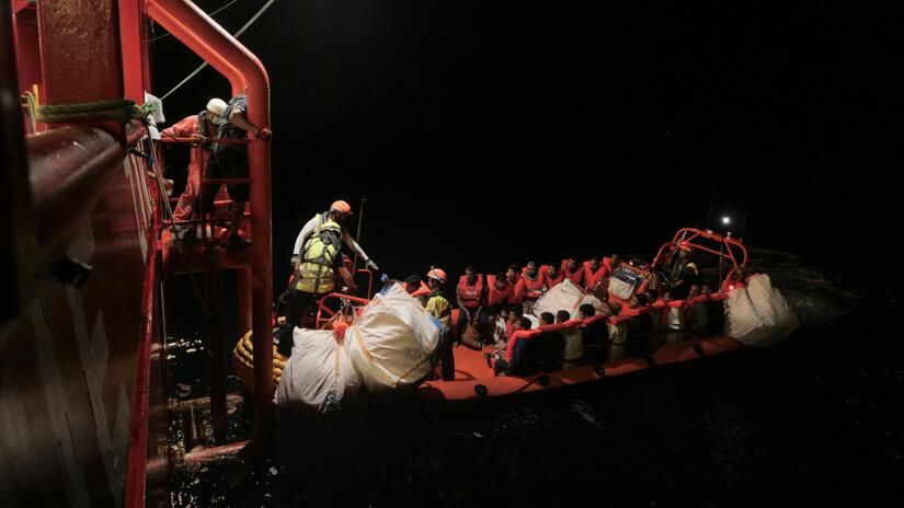 An SOS Mediterranee team transports a group of rescued migrants to the Ocean Viking rescue ship in a RHIB (rigid-hulled inflatable boat) in pitch black in the early hours of 12 August.