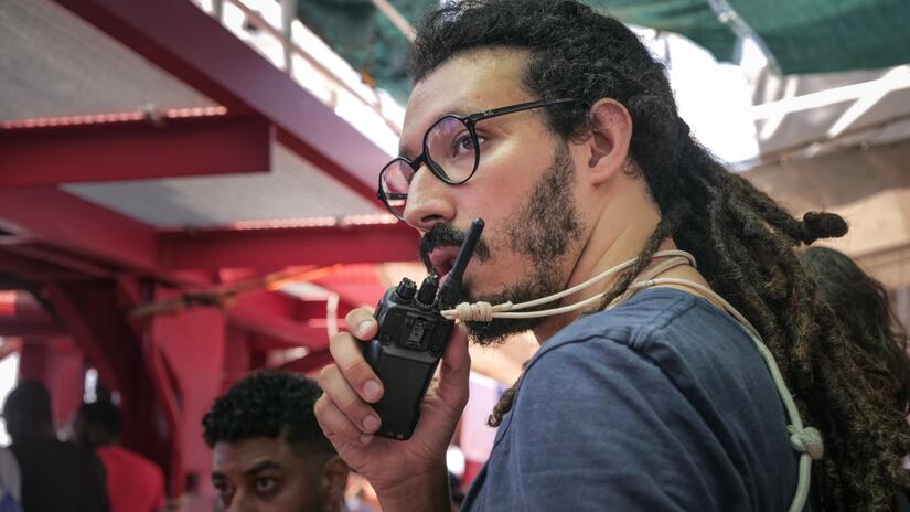 IFRC Protection Team Leader, Ahmed Bentalha, communicates to crewmembers on board the Ocean Viking ship via walkie talkie as they complete rescue after rescue in the Central Mediterranean in August 2023.