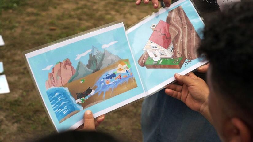 People attending a disaster preparedness workshop in western El Salvador look at images explaining the risks and potential impacts of tidal surges and landslides.