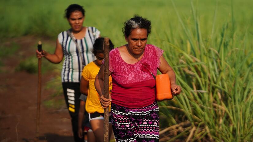 Rosa walks to her farmland with her daughter and granddaughter to harvest some of their crops.