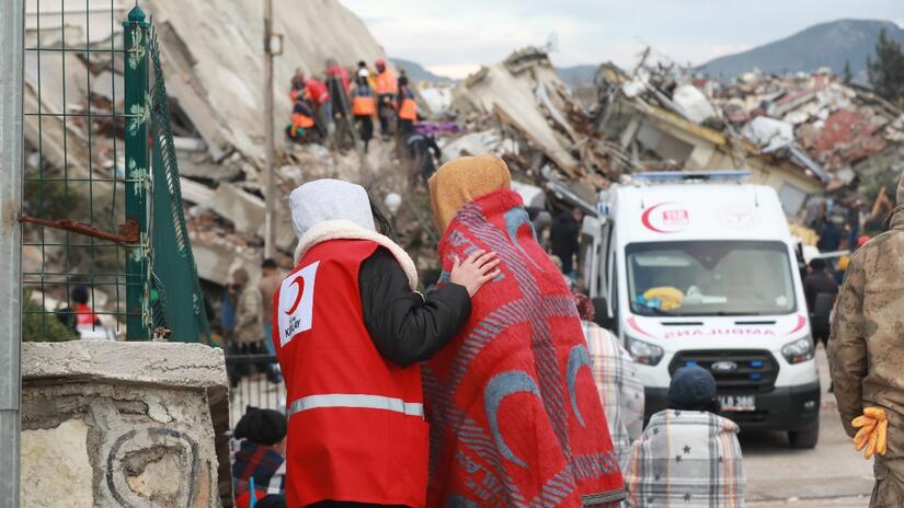 A Turkish Red Crescent volunteer offers a blanket to and comforts a woman who was affected by devastating earthquakes in February 2023.