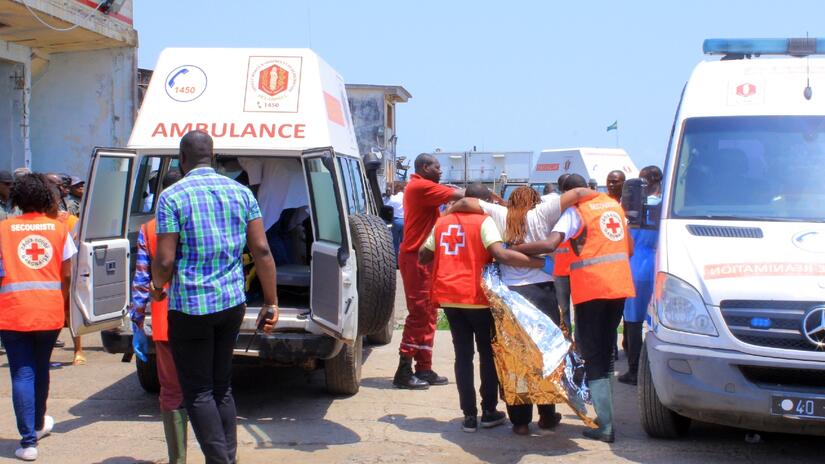 Des volontaires de la Croix-Rouge gabonaise transportent les personnes sauvées du ferry Esther Miracle vers des ambulances afin qu'elles soient transportées à l'hôpital pour un traitement médical urgent.