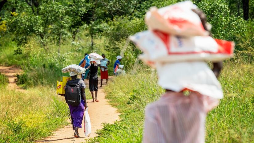 A community in Zimbabwe carry food items received from the Zimbabwe and Finnish Red Cross.