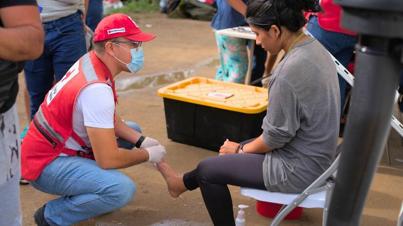 Ángel Zelaya presta atendimento pré-hospitalar a uma mulher com feridas nos pés, no Posto de Atendimento Humanitário Danlí.