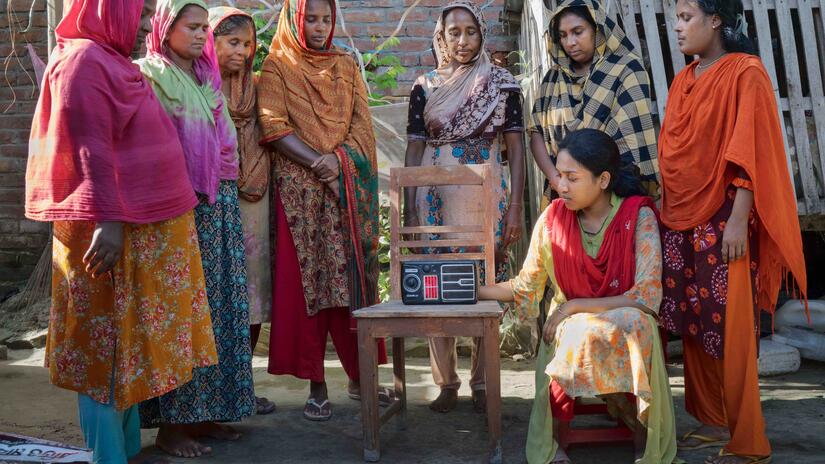 Women listen to radio programme featuring messages about how to best handle extreme heatwaves.