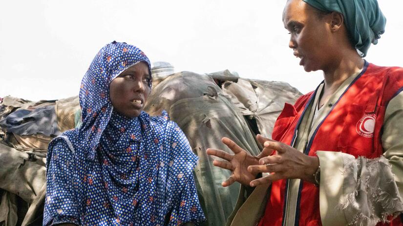 A Djibouti Red Crescent volunteer talks to a migrant living in an informal settlement.