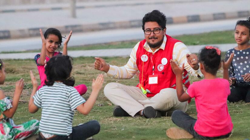 Un voluntario de la Media Luna Roja Libia juega con un grupo de niñas tras las inundaciones en la ciudad de Derna.