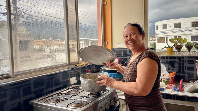 Belkis Colmenares sonríe a la cámara desde su cocina. Ella fue una de las personas migrantes que recibió ayuda en efectivo de la Cruz Roja Ecuatoriana para cubrir necesidades básicas como alimentos, alquiler y medicinas.