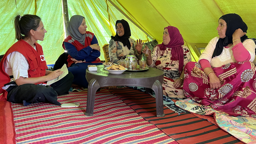 Mónica Posada, coordinadora de Participación Comunitaria y Rendición de Cuentas de la IFRC, y Maryam Chtitihi, voluntaria de la Media Luna Roja Marroquí, conversan con mujeres de la aldea de Tagadirt para asegurarse de que tengan una voz protagonista mientras su comunidad traza el camino hacia la recuperación. 