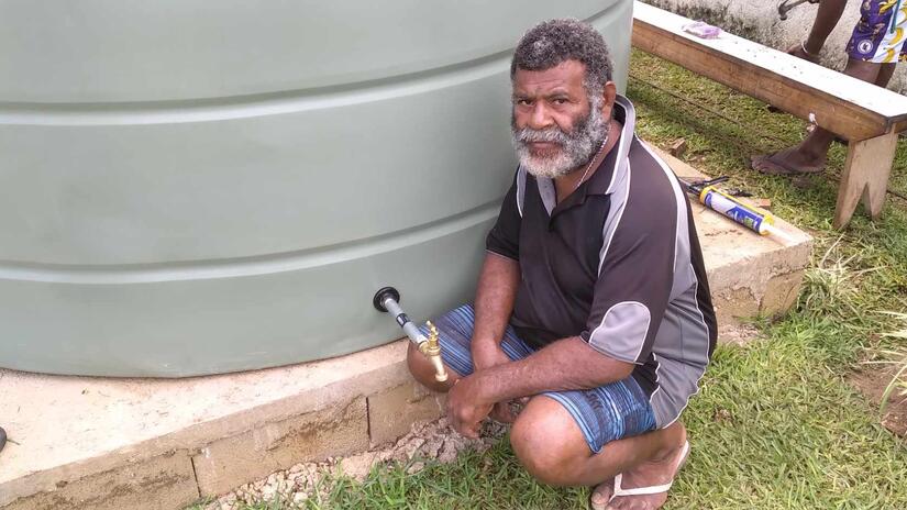 Eric Tangarasi, de 51 años, jefe de la estación de Mango, sentado sobre los cimientos del depósito de agua construido con la ayuda de personas jóvenes voluntarias de la Cruz Roja de Vanuatu.