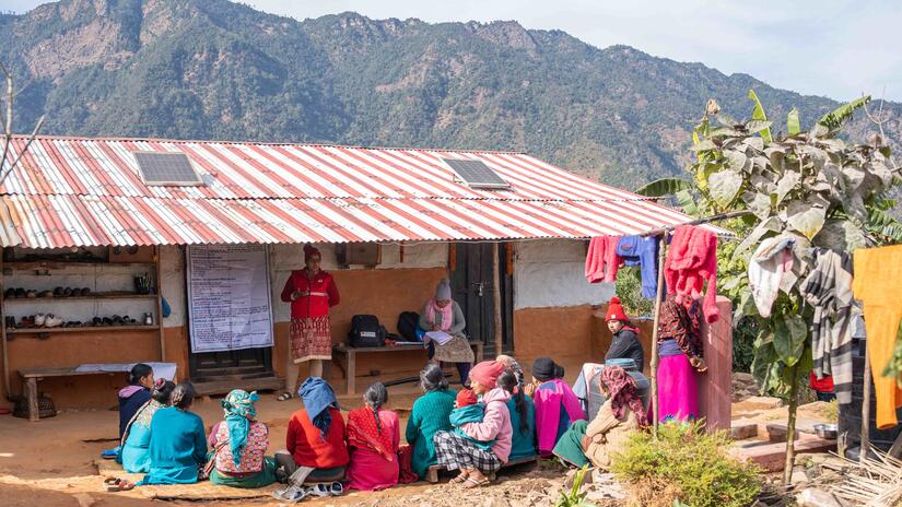 Nepal Red Cross volunteer Muna demonstrates proper handwashing steps to school children gathered at a local school.