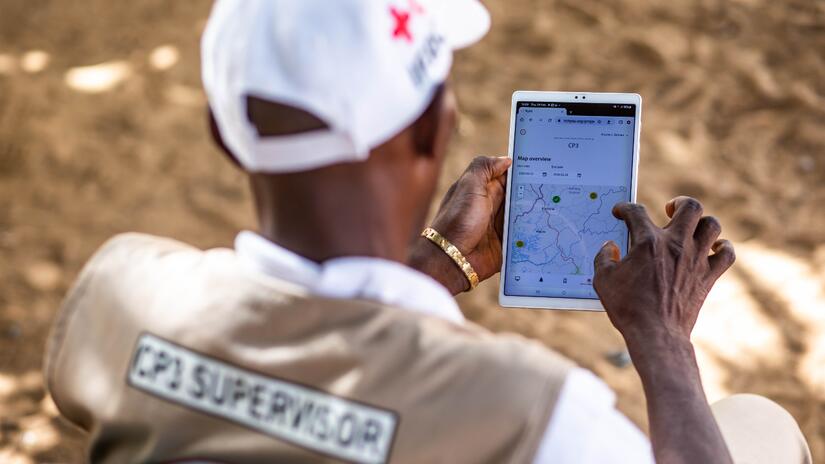 Jobel, a supervisor with the Community Epidemic and Pandemic Preparedness Programme (CP3), uses a tablet to access a digital community-based surveillance system, enabling him to track health alerts in Kambia district and quickly escalate cases to local health authorities.