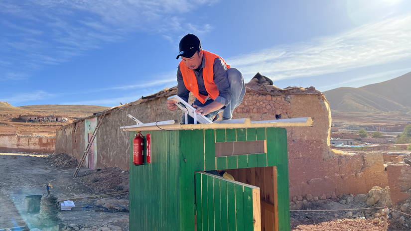 A volunteer with the Moroccan Red Crescent puts the finishing touches on a shower stall for a community that lost nearly all its access to clean water following the September 2023 Earthquake.