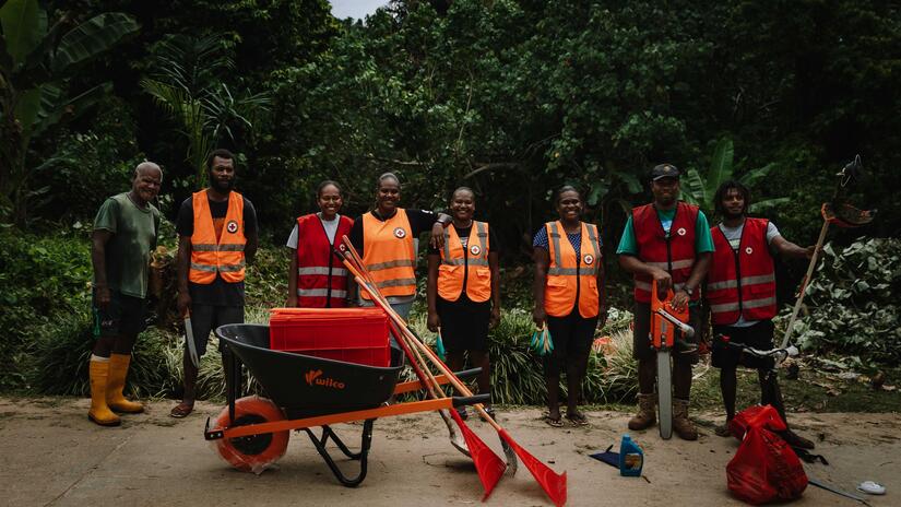 Members of the clean up crew stand behind the wheelbarrow, rakes, shovels and other tools they bought in order to clear vegetation and garbage from the river that runs near their town.
