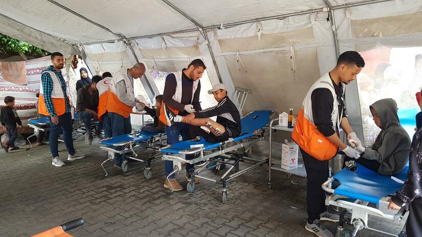 في النقطة الطبية في جباليا، يقوم متطوعو جمعية الهلال الأحمر الفلسطيني برعاية المرضى.
