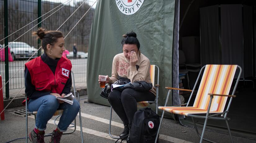 À la frontière slovaque avec l'Ukraine, une réfugiée ukrainienne nommée Iryna est réconfortée par un délégué de l'IFRC dans un poste de la Croix-Rouge slovaque mis en place pour aider les réfugiés en leur apportant les premiers soins, un soutien psychosocial et divers autres services essentiels pour les familles fuyant le conflit.