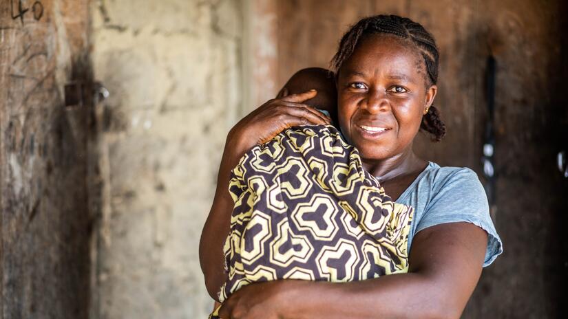 Baindu tient dans ses bras son fils Senesie en mars 2024, après son rétablissement complet du paludisme.