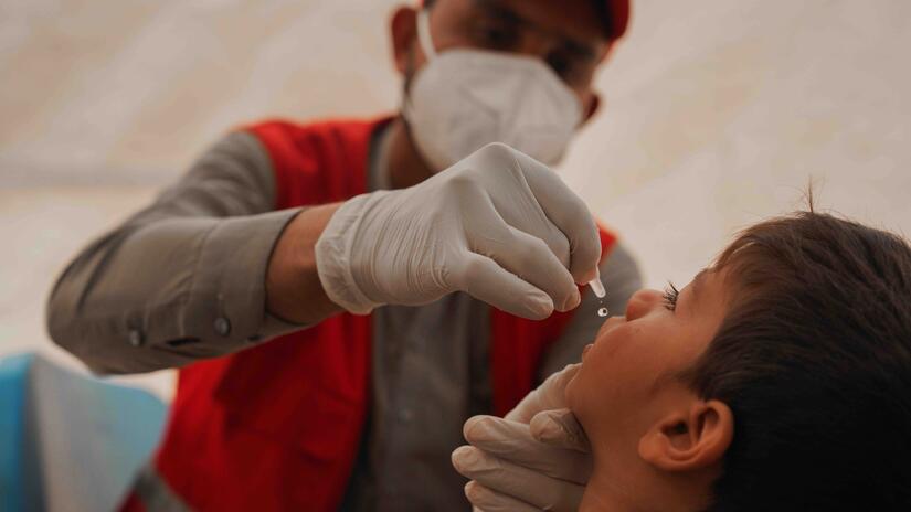 Les jeunes enfants sont particulièrement vulnérables à de nombreuses maladies infectieuses. Ici, un membre de l'équipe mobile de santé du Croissant-Rouge afghan administre un vaccin oral contre la polio à un petit enfant dans la province de Helmand.