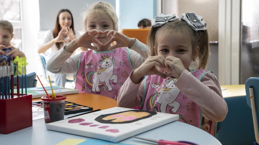 Niñas hacen el signo del corazón con las manos durante una sesión de arteterapia en la filial de la Cruz Roja Búlgara en Plovdiv, en el marco del proyecto EU4Health.