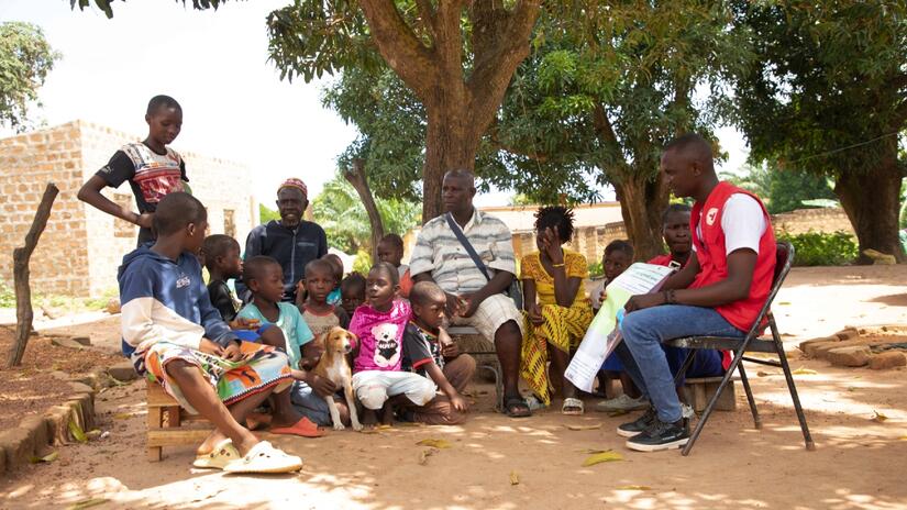 A Guinea Red Cross volunteer with the Community Epidemic and Pandemic Preparedness Programme (CP3) speaks to a family about the risks of rabies and how they can protect themselves.