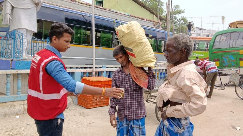 Un volontaire de la Croix-Rouge indienne distribue de l'eau à deux personnes pendant une vague de chaleur.