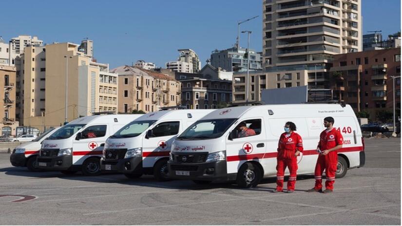 Un grupo de miembros del Punto de Servicio Humanitario de la Cruz Roja Libanesa que atiende a personas migrantes que han naufragado, afuera de sus vehículos de intervención.