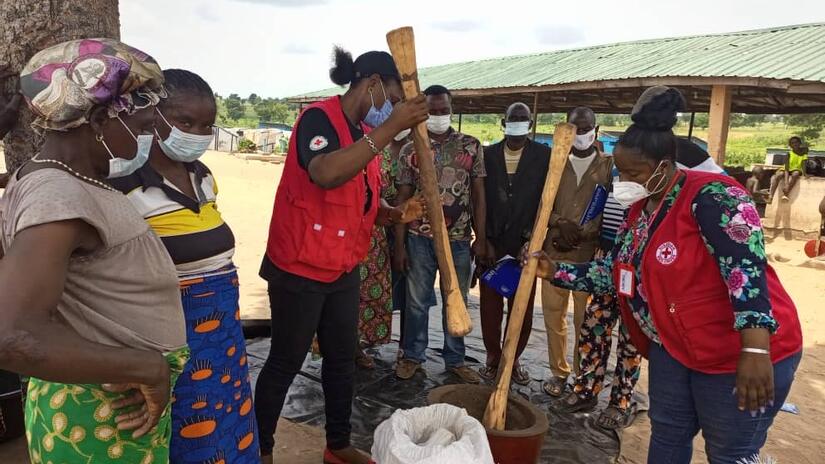 Nigerian Red Cross volunteers show people how to make fertilizers using natural ingredients such as rice husks, which they first break up by pounding them with large wooden pestles.