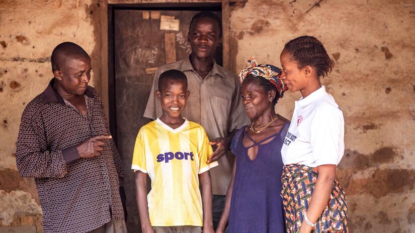 Abu smiles as he stands surrounded by his parents, brother, and volunteer, Rebecca.