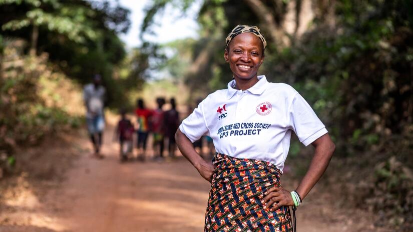 Rebecca, volontaire, se tient fièrement devant un groupe d'enfants du village de Laya Dee qu'elle surveille pour s'assurer qu'ils reçoivent le soutien sanitaire dont ils ont besoin.