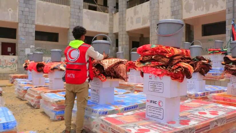 A Yemen Red Crescent volunteer stacks up household supplies that will be given to people who lost their homes due to severe and sudden flooding.