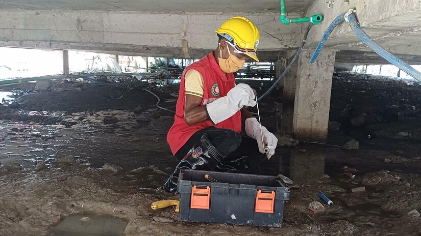 Bangladesh Red Crescent volunteer Abdul Hamid works underneath an apartment block where he is maintaining pipes that bring cooking gas that is produced from biological waste.