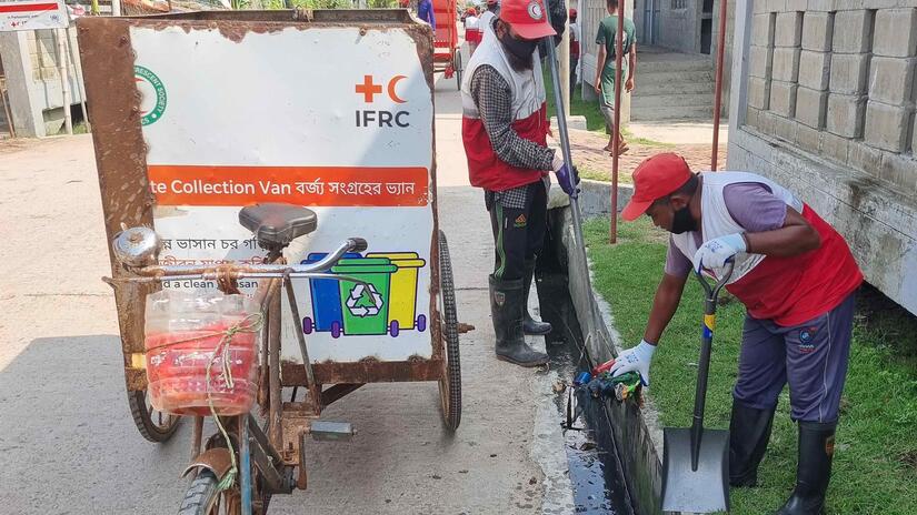Bangladesh Red Crescent volunteer Jafor Alam and another volunteer clean a narrow concrete water canal in order to prevent blockages that can lead to flooding.