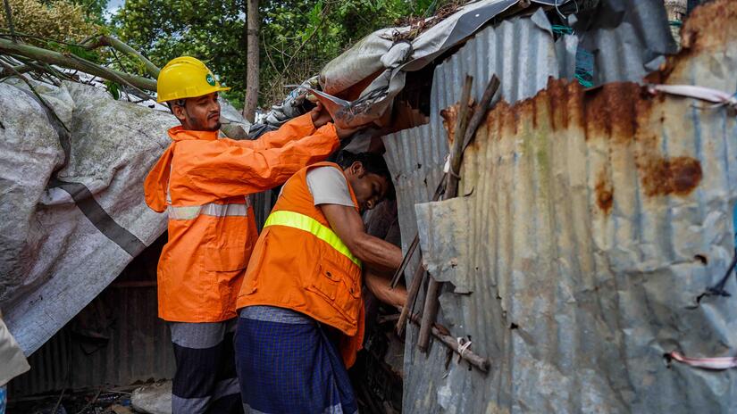 Two volunteers in the Cox's Bazar settlement in Bangladesh work to strengthen a shelter in Camp 26 before cyclone Mocha hit in 2023.