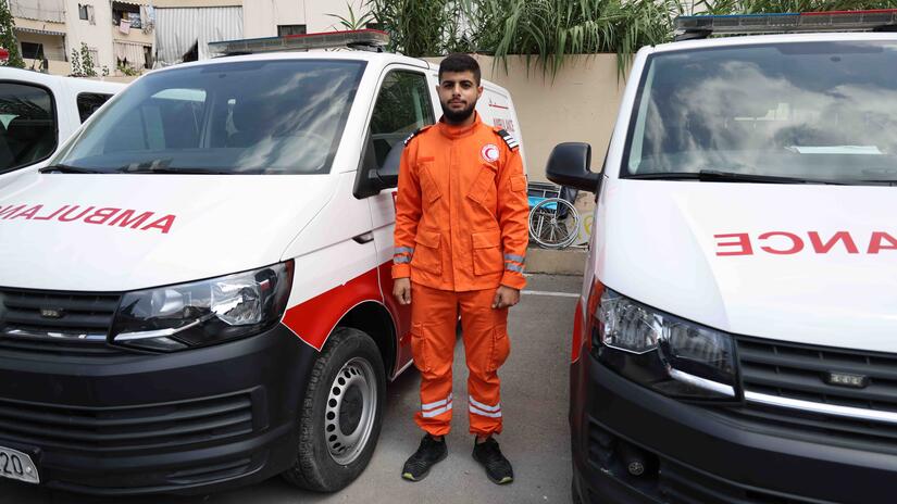 Proudly wearing his Palestine Red Crescent emergency medical services uniform, 19-year-old Ahmad Marwan El Issa stands in front of an ambulance, ready to respond at any time.