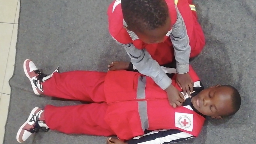 Two young children take part in a first-aid learning session organised by the Cameroon Red Cross.