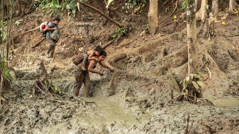 Con cada paso, esta mujer que lleva a un niño a la espalda, se hunde más en el barro, y su lucha por completar la caminata se hace cada vez más desalentadora.