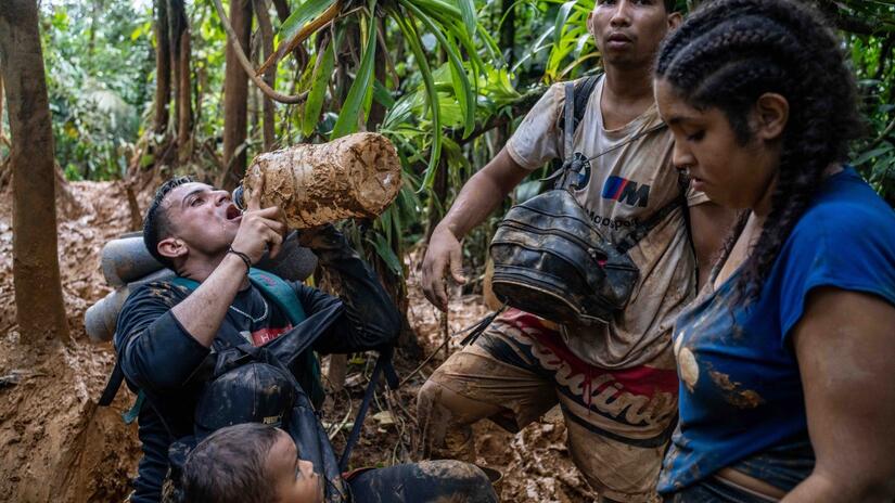 En esta imagen, tomada en el corazón de la selva, un grupo de migrantes comparte las últimas gotas de agua en una botella plástica.