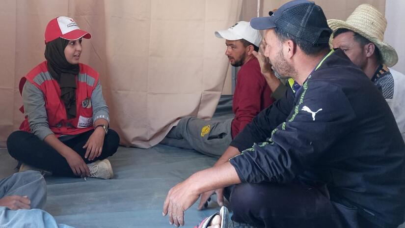 Moroccan Red Crescent shelter officer Naima sits down with community workers to train them on the process and techniques of installing temporary shelters.