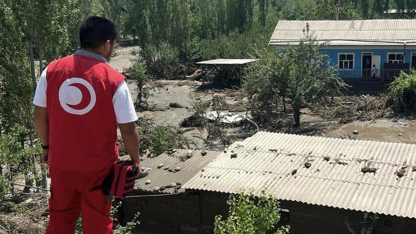 A volunteer with the Kyrgyszstan Red Crescent looks over extensive damage caused to a community by heavy flooding in June 2024.